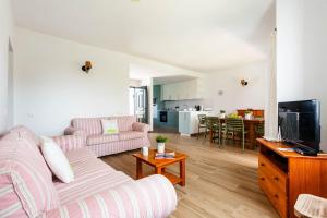 Una sala de estar con un sofá y un televisor. en Villa Juana - Torre Solí, en Son Bou