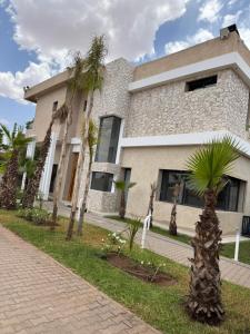 a building with palm trees in front of it at La Villa K Marrakech jacuzzi chauffé in Marrakech