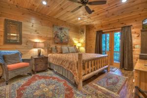 ein Schlafzimmer mit einem Bett und einem Stuhl in einer Hütte in der Unterkunft Pursuit of Happiness Mountain luxury hot tub big-screen TVs pet-friendly in Mineral Bluff