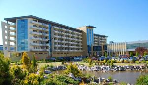 a large building in a parking lot next to a river at Prywatny Apartament w Arka Medical Spa in Kołobrzeg