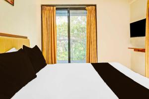 a bedroom with a white bed and a window at Townhouse Oak Pune Future Towers in Pune +24 photos