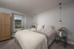 a bedroom with a white bed and a window at Berlewen, Mousehole in Mousehole