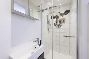 a white bathroom with a shower and a sink at Berlewen, Mousehole in Mousehole +30 photos