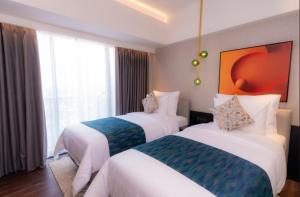 a hotel room with two beds and a large window at Herloom Hotel & Residence BSD Tangerang in Tangerang