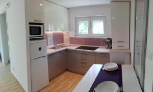 una pequeña cocina con electrodomésticos blancos y paredes rosas. en Judit Apartman, en Vonyarcvashegy
