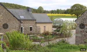 an old stone house with a garden and a greenhouse at Gîte de charme avec piscine au cœur de la nature in Hénon