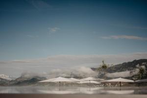 a group of umbrellas on a beach with clouds at Hotel Berghof - St Johann in Salzburg in Sankt Johann im Pongau