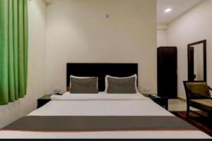 a bedroom with a large bed with a green curtain at RROOMS Hotel Riddhi Inn in Lucknow