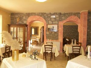 a restaurant with tables and chairs and a stone wall at Albergo Elisa in Comano