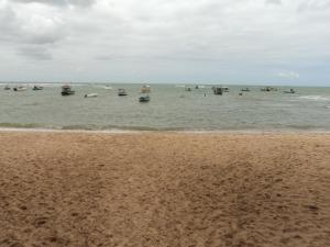 un groupe de bateaux dans l'eau sur une plage dans l'établissement Enseada Praia do Forte, à Praia do Forte