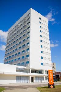 a white building with an orange sign in front of it at Intercity Gravataí in Gravataí
