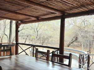 una mesa de madera y sillas en un porche en Papagaai 2409, en Marloth Park