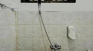 a water hose hooked up to a soap dispenser on a wall at Capital O 1362 Ciliwung Guest House Syariah in Malang +78 photos