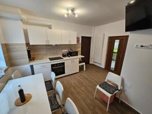 a kitchen with white cabinets and a table and chairs at Casa Lia Voroneț in Voroneţ