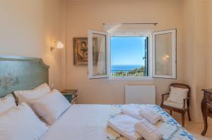 a bedroom with a bed and a window with the ocean at Villa Oliva - Majestic Views in Andros +24 photos