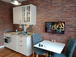 a kitchen with white cabinets and a brick wall at Penzion V peřině in Trojanovice