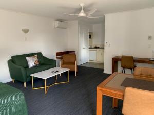 a living room with a green couch and a table at Armidale Pines Motel in Armidale