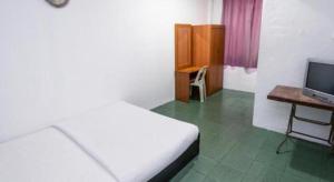 a bedroom with a bed and a desk and a television at OYO 89706 To-day Hotel in Sibu