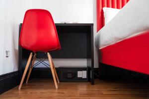a red chair sitting next to a desk in a bedroom at easyHotel Newcastle in Newcastle upon Tyne