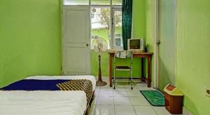 バンドンにあるSPOT ON 91325 Pondok Hijau Guest House Syariahの緑の壁と扇風機付きの机のある寝室