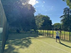un uomo che tiene una racchetta da tennis su un campo da tennis di Maison du gardien de Logempré a Pont-Saint-Pierre