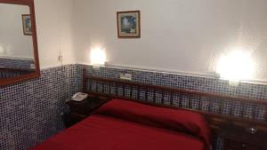 a bedroom with a red bed with a mirror and a phone at Pensión Campoy in Murcia