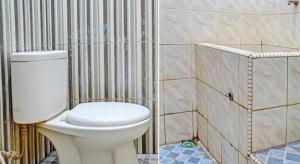 a bathroom with a toilet and a tiled wall at Hotel O Nusantara in Banyuwangi