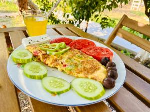 a plate of pizza and vegetables and a glass of orange juice at Simadhes Garden Rooms in Himare