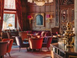 a restaurant with tables and chairs and a chandelier at Fairmont Hotel Vier Jahreszeiten in Hamburg