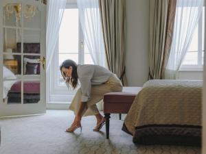 a woman kneeling on a bed in a hotel room at Fairmont Hotel Vier Jahreszeiten in Hamburg +37 photos