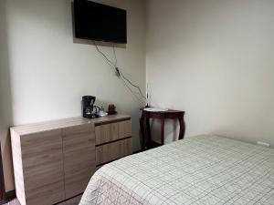 a bedroom with a bed and a tv on the wall at Alojamiento Privado in Otavalo