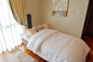 Una cama blanca en una habitación con ventana. en ゲストハウスえらぶー, en Wadomari