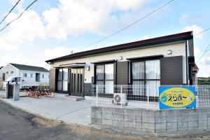 una pequeña casa con un cartel delante en ゲストハウスえらぶー, en Wadomari