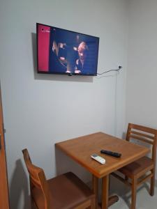 a television hanging on a wall above a wooden table at HOTEL Pousada ACONCHEGO Promissão in Promissão