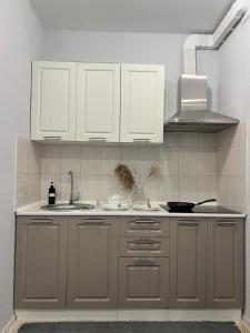 une cuisine avec des armoires blanches et un évier dans l'établissement Двухкомнатная квартира в ЖК Green Plaza, à Aktau