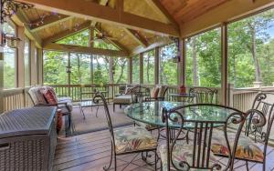 eine abgeschirmte Veranda mit Tischen und Stühlen in der Unterkunft Plummer Lodge - Relax on the porch at this luxury Big Canoe getaway in Jasper