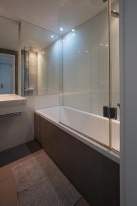 a bathroom with a tub and a glass shower at SKAU Eurovea Duplex Apartment Danube Exclusive View Free Parking in Bratislava +11 photos