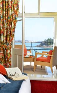 a bedroom with a bed with a book and a balcony at Hotel Villa Reine Hortense in Dinard