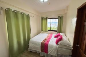 a bedroom with a bed with green curtains and a window at Pink Ocean Diving Resort Sabang Puerto Galera in Puerto Galera