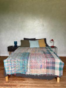 a bedroom with a bed with a colorful blanket and a lamp at Belle chambre au coeur de Cassel in Cassel +2 photos