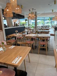 a restaurant with wooden tables and chairs and chandeliers at Waveview Premium Apartment Międzyzdroje in Międzyzdroje