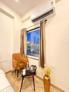 a bedroom with a window and a chair and a table at Hotel Kings Inn in Jaipur