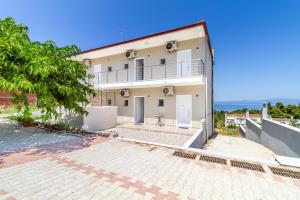 a white house with a balcony and the ocean at Calua SeaView Rooms in Kriopigi