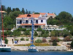 a sail boat in the water in front of a house at Nicolas Rooms in Fiskardo
