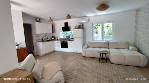 a living room with white furniture and a kitchen at Casa Nova in Njivice
