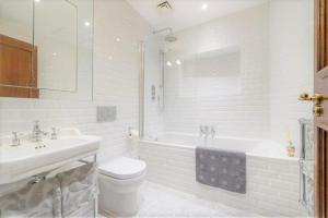 a white bathroom with a sink and a tub and a toilet at Luxury flat in Covent Garden in London