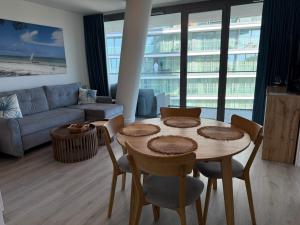 a living room with a table and chairs and a couch at Apartament Blue Lagoon A542 w Wave Międzyzdroje in Międzyzdroje