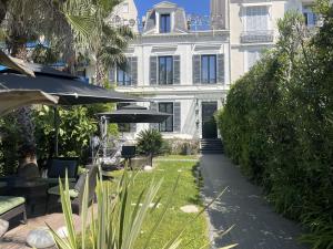 a large white building with an umbrella and a garden at Villa Pruly Hotel Cannes Centre in Cannes