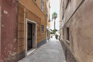 an alley between two buildings with a palm tree at Apartment facing the sea and Navebus Porto Antico in Genova