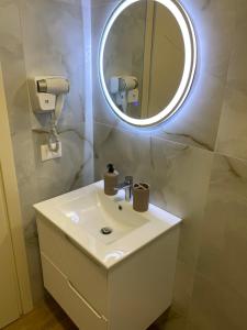 ein Badezimmer mit einem weißen Waschbecken und einem Spiegel in der Unterkunft Hajdini Apartament & Studios in Sarandë + 35 Fotos